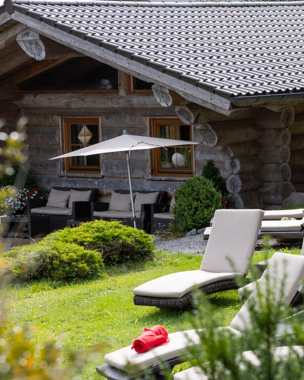 Spa-Ansicht auf die Blockhütte, davor Gartenwiese mit Liegen zum entspannen vom Hotel Konradshof in Besenfeld